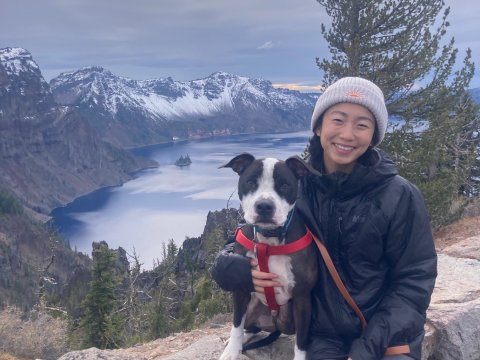 A woman and her dog smile with the Gorge behind them