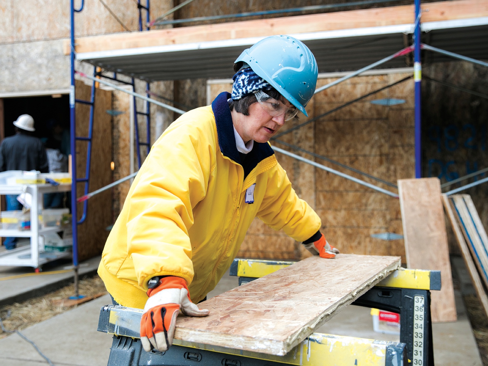 Julie Christiansen placing lumber on a sawhorse at a construction site