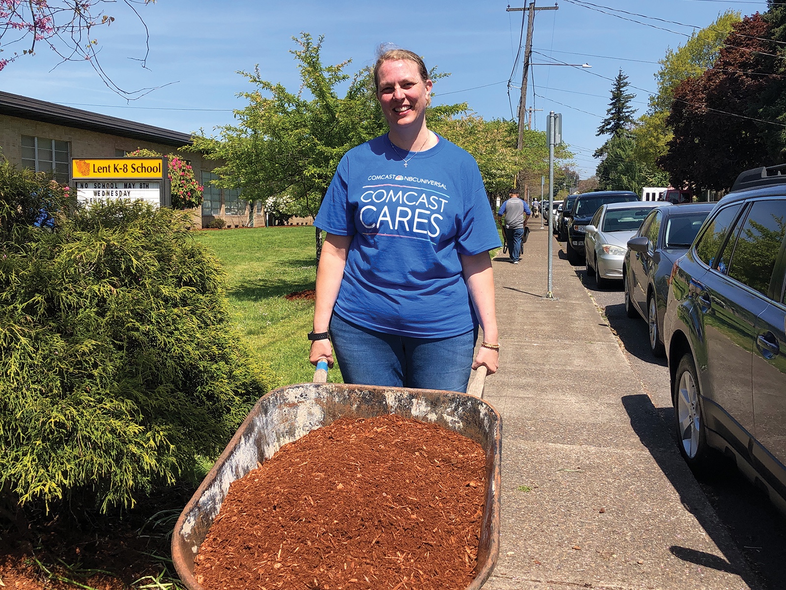 Kori Gregg pushing a wheelbarrow full of mulch