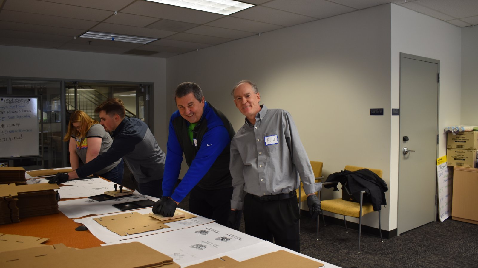 Two volunteers smile while building STEM Kits