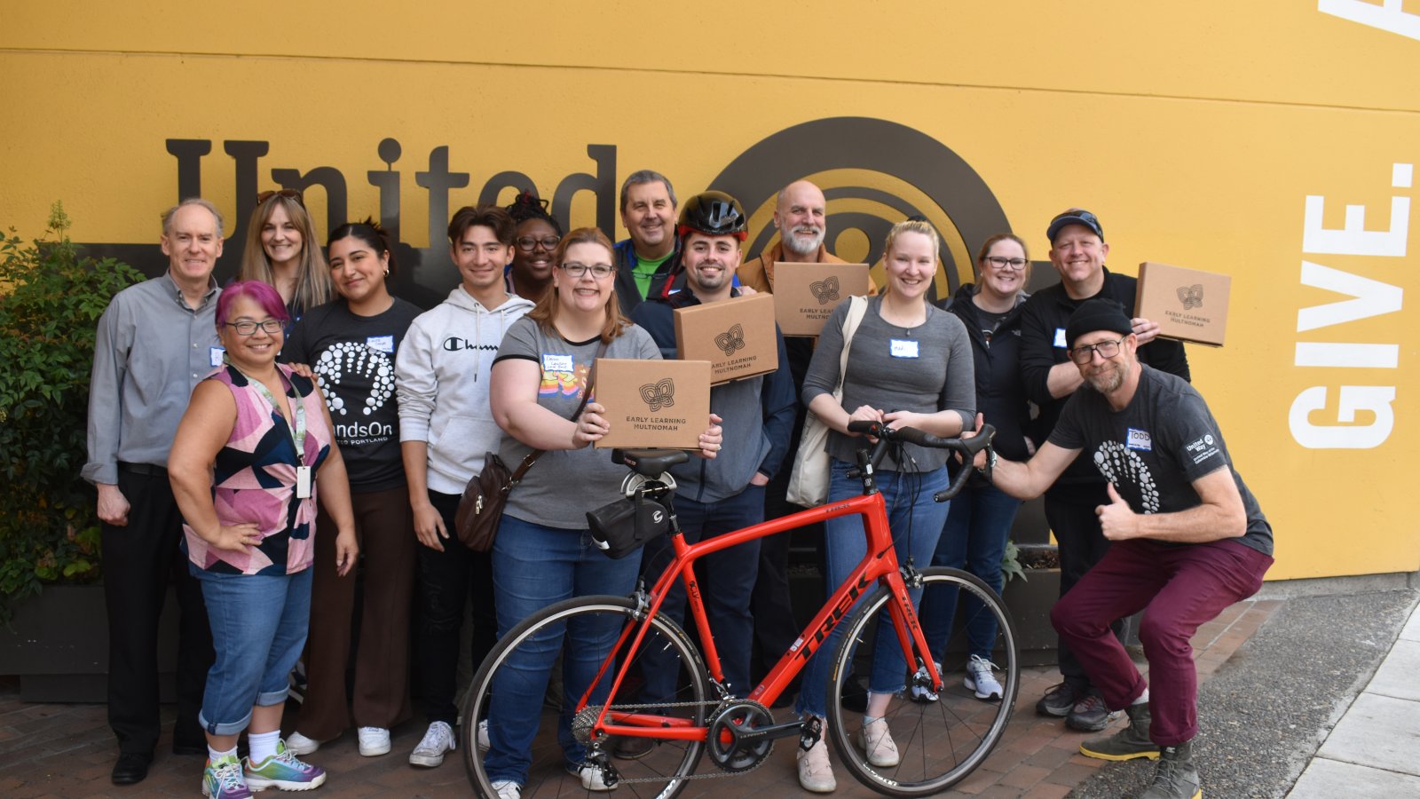 A group of 13 volunteers from WaFd Bank and United Way Staff members pose with completed STEM kits. 