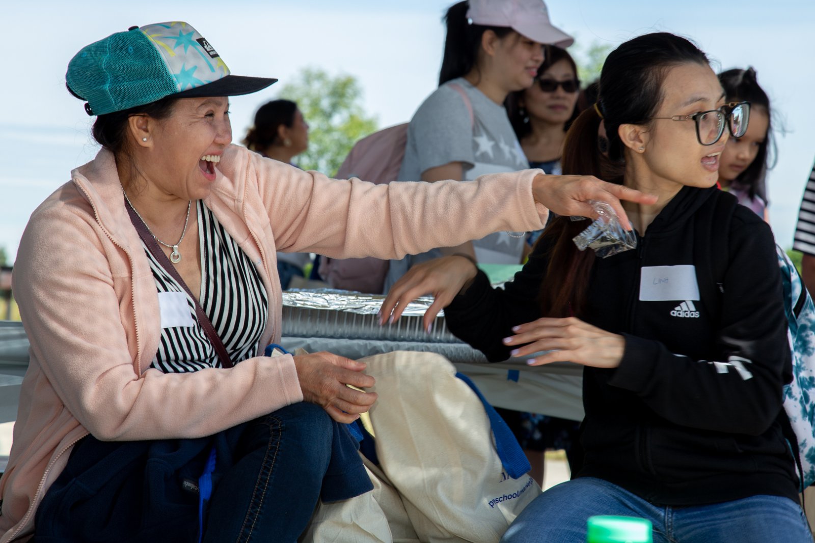 A woman laughs and points at something outside the frame