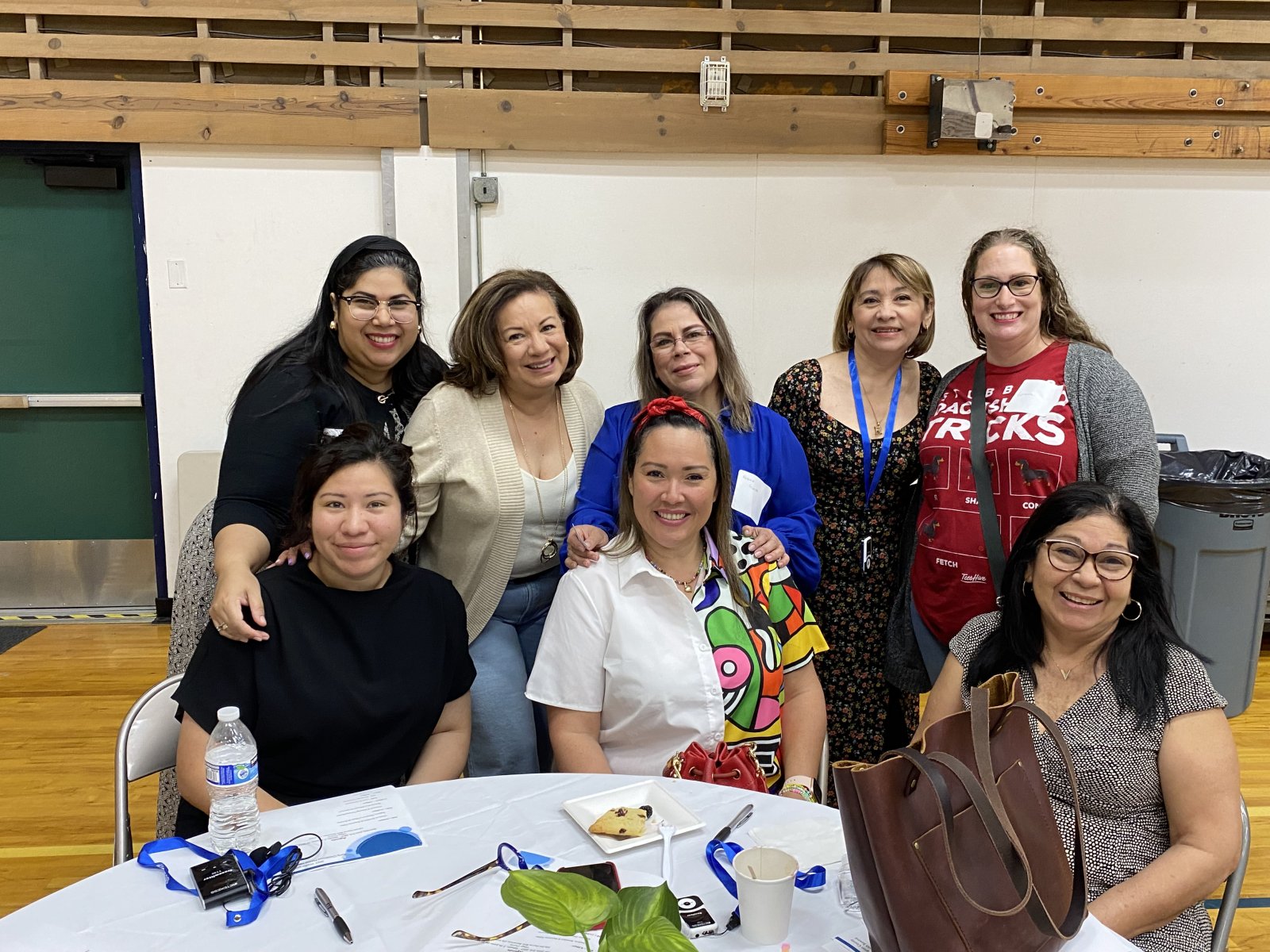 A group of women sit around a table smiling