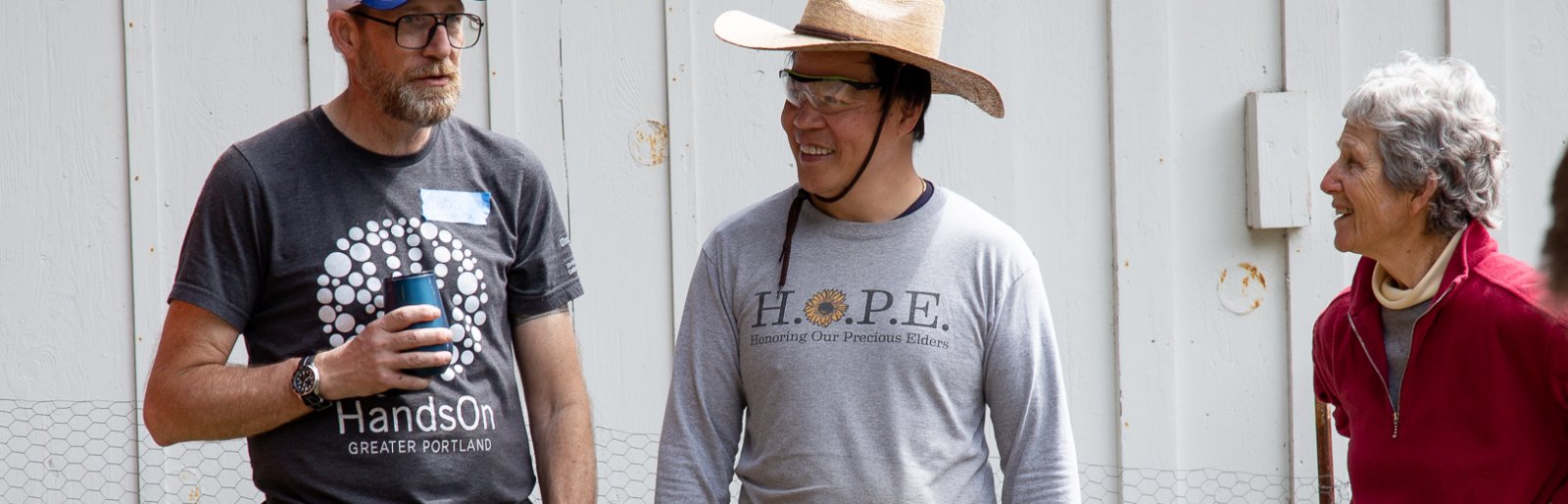 two men in Hands On Greater Portland shirts talk while an older woman looks on