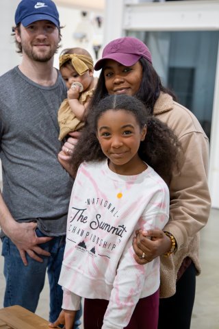 A child and her family smile for the camera