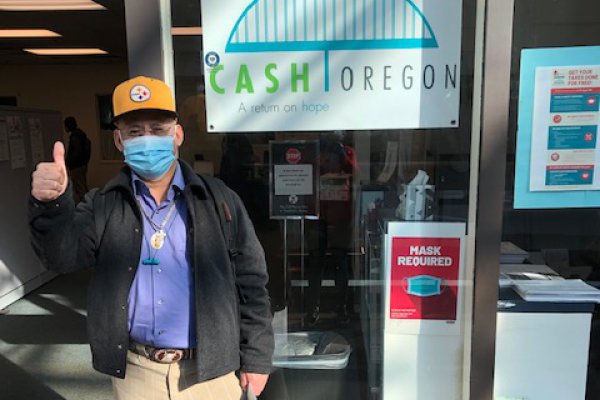 A MFS CASH Oregon tax prep volunteer thumbs up outside the group's office.