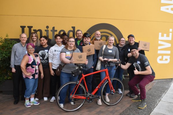 A group of 13 volunteers from WaFd Bank and United Way Staff members pose with completed STEM kits. 