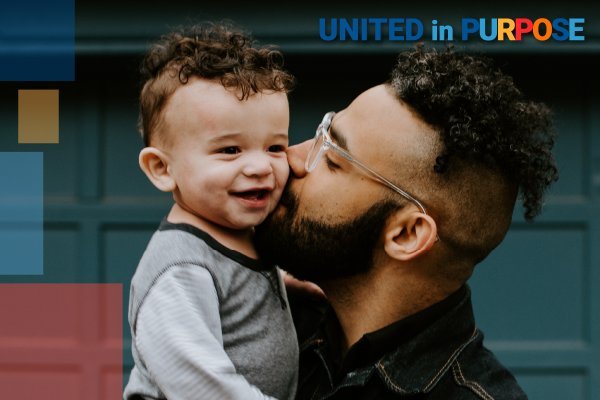 A man with glasses kisses a baby boy on the cheek