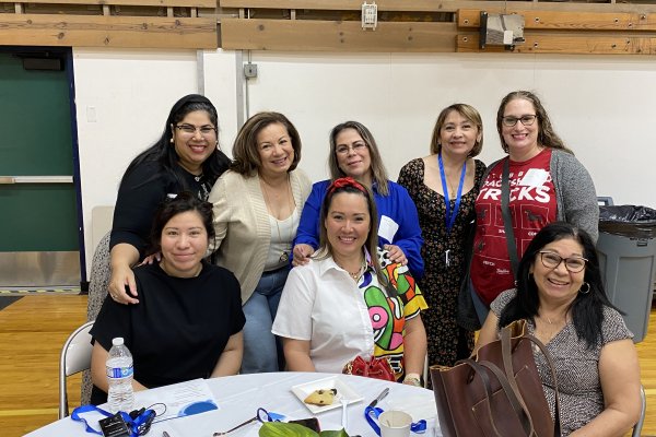 A group of women sit around a table smiling