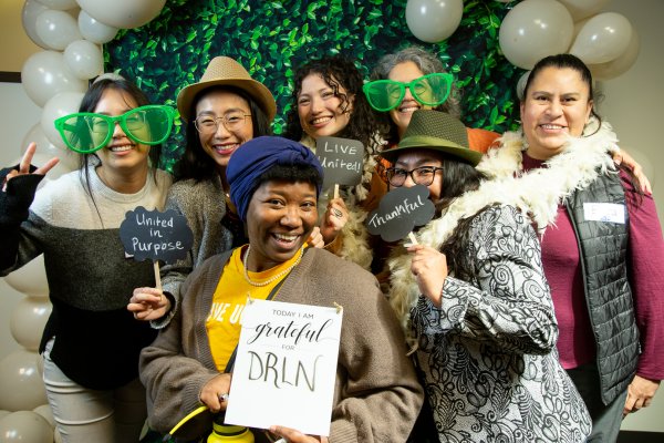 A group of women smile holding props in a photo booth