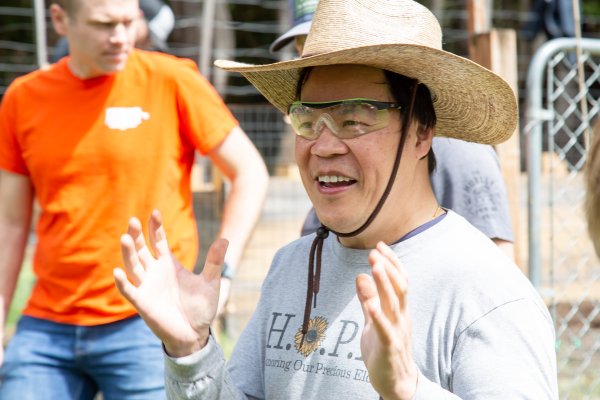 A man in a hat expresses with his hands and smiles