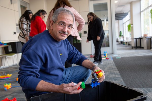 A man hold legos and smiles for the camera