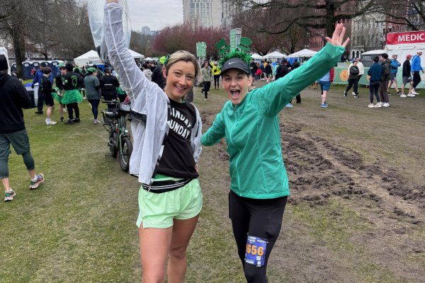 Two women celebrate with their hands in the air in a grassy field
