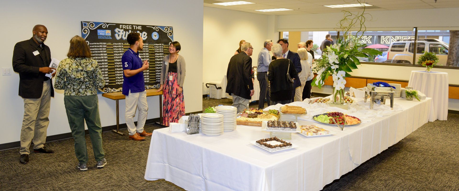 A group of people utilizing our community space with a spread of food on the table.