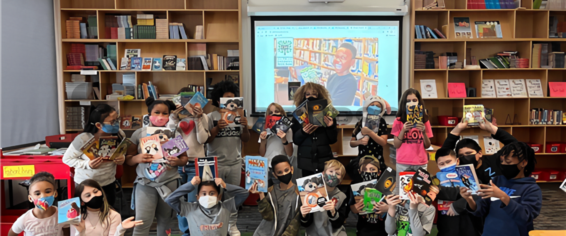 A group of masked kids hold books up in front of shelves lined with more books.