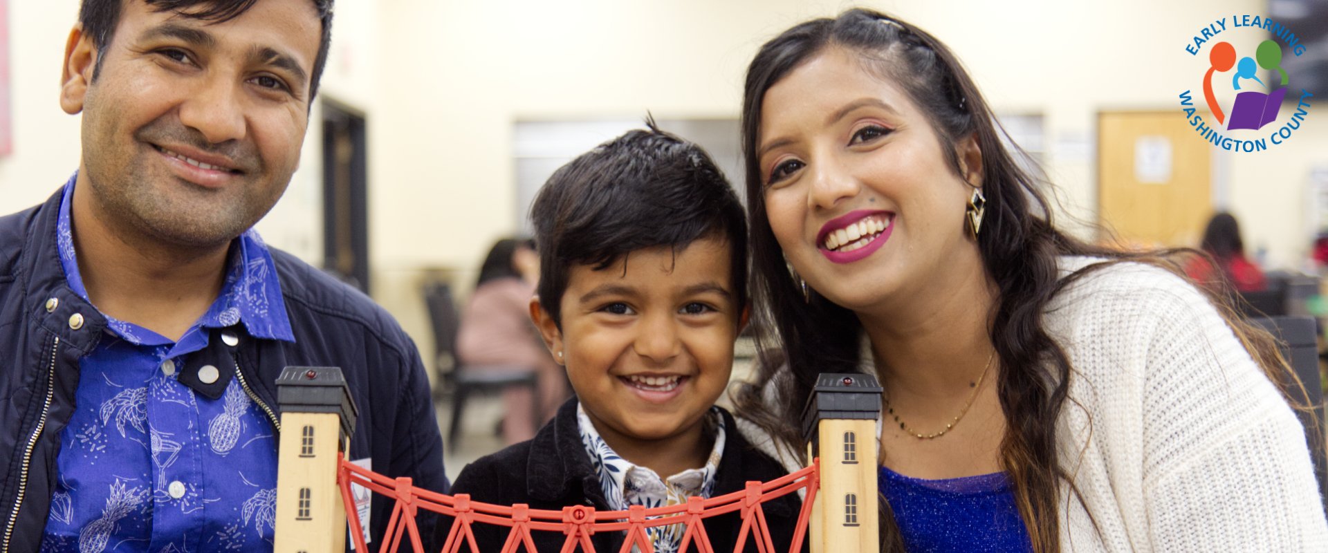 A father mother and child smile while holding the bridge they built