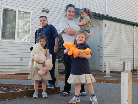 A family hugging in front of a home