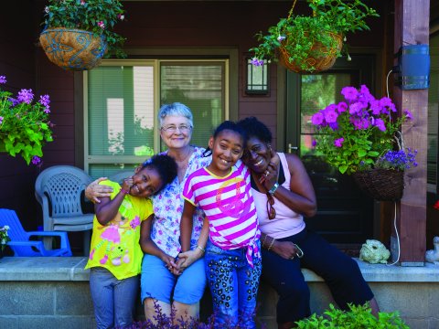 A family sits on their porch posing for a photo
