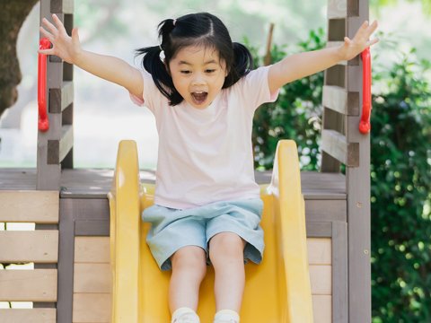 A little girl on a playground slide.