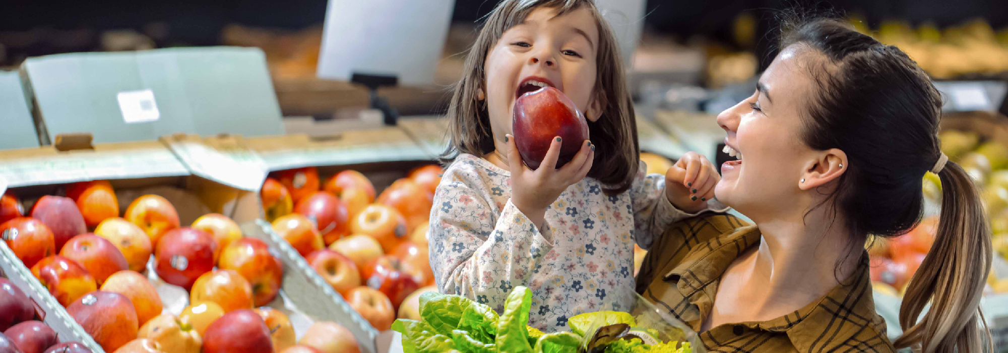 A mother and daughter smile while grocery shopping