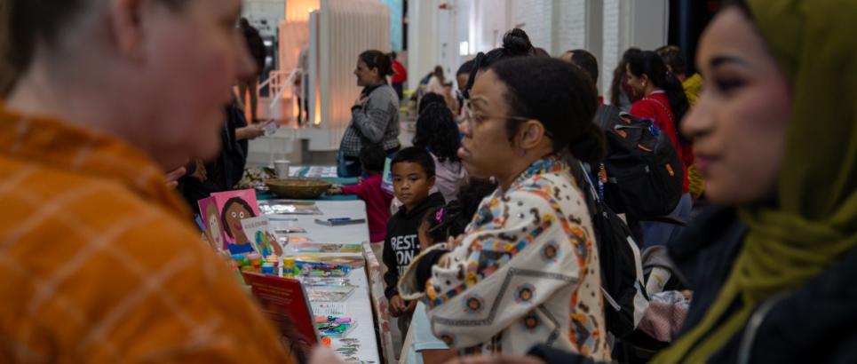 A large group of adults mingle while kids smile and play