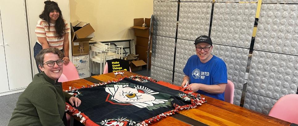A group of three people work on a blanket
