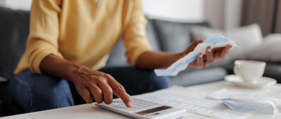 A picture of a woman checking bills and typing on a calculator