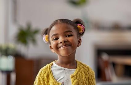 a girl in a yellow sweater and white tshirt smiles wide