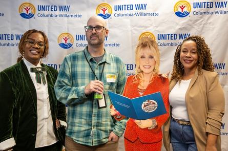 three people stand with a dolly parton cutout smiling