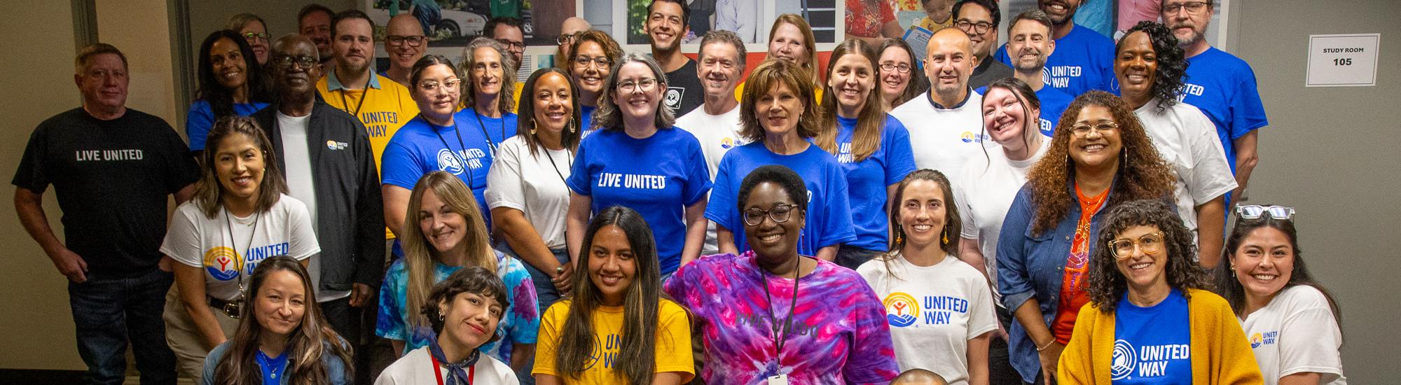 A large group of people smile in a group, many wearing United Way branded shirts