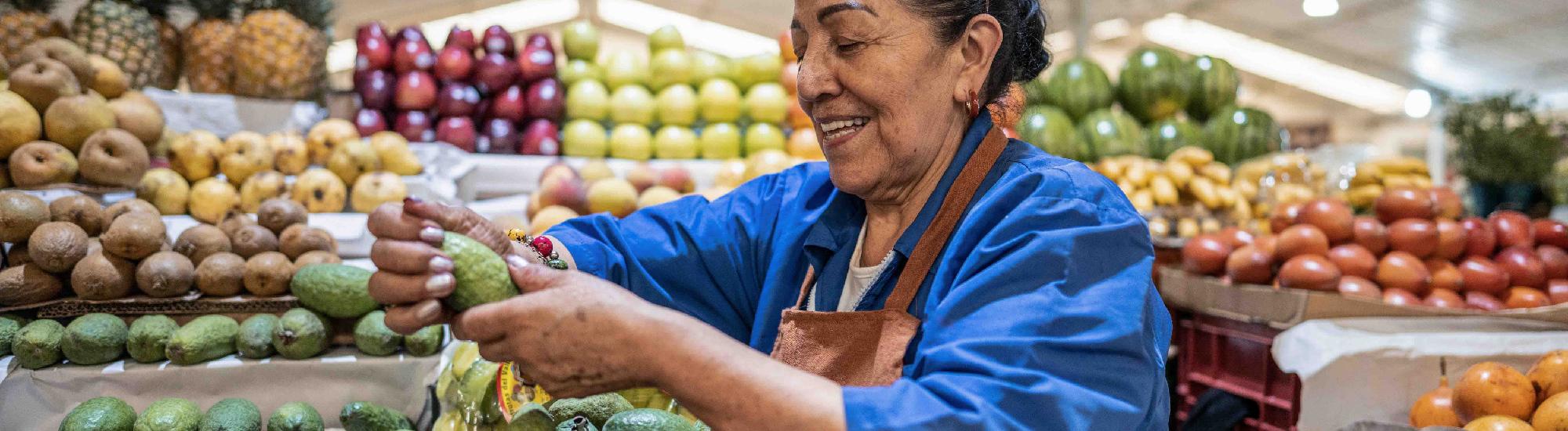 A woman smiling picks up an avocado