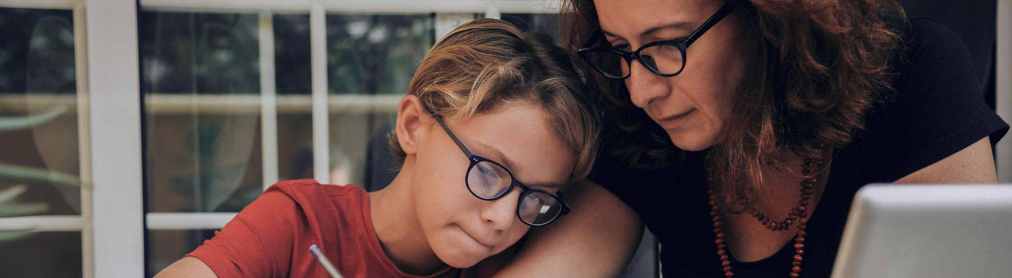 a woman and child in glasses look over some paperwork