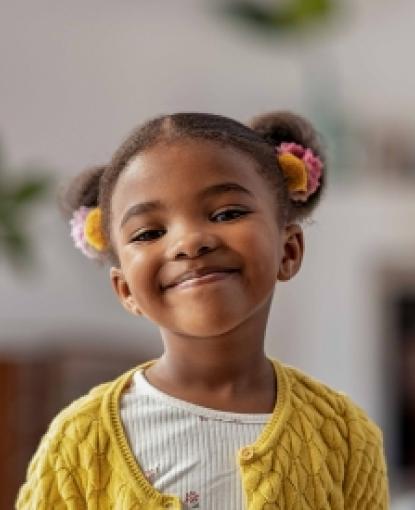a girl in a yellow sweater and white tshirt smiles wide