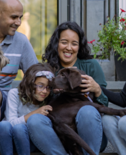 A photo of a family and a dog sitting on the steps of a house