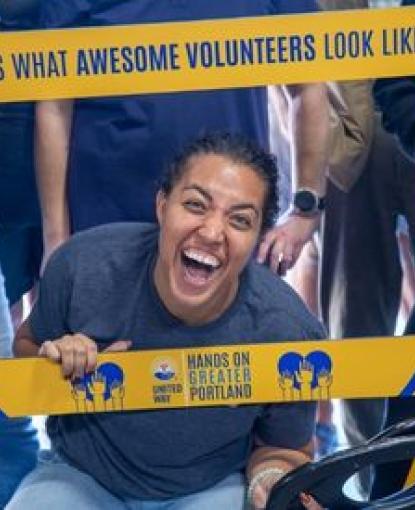 a woman smiling brightly in a yellow frame sign that says this is what awesome volunteers look like