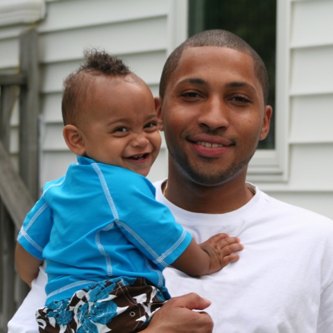 portrait of a young father holding a smiling toddler